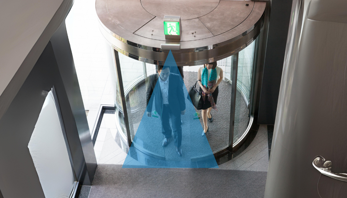 Top view of a company entrance hall where 2 people are there. A blue beam vertically above the airlock is displayed to indicate the flow measurement.